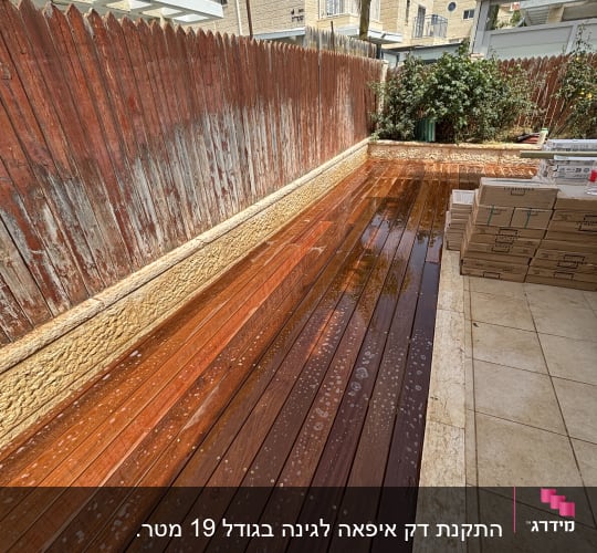 דק עץ חדש בגינה עם גדר עץ וצמחייה